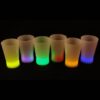 A group of six shot glasses that are lit up.