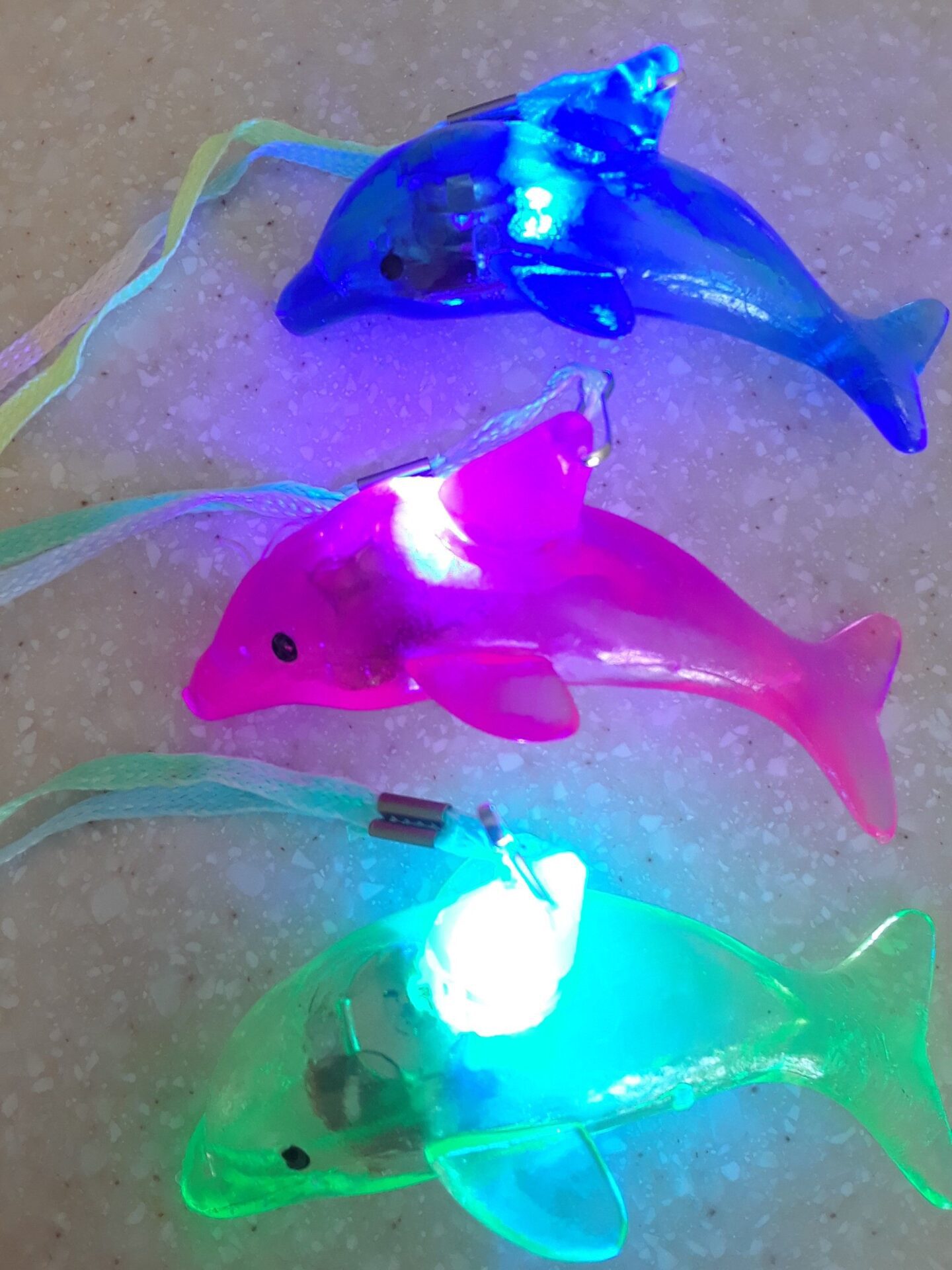 A group of three plastic dolphins with lights on them.