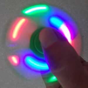 A person is spinning a colorful fidget spinner.