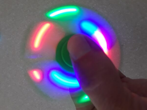 A person is spinning a colorful fidget spinner.