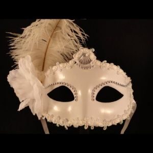 A white mask with feathers and rhinestones on it.