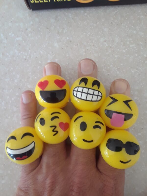 A hand holding some yellow smiley face rings