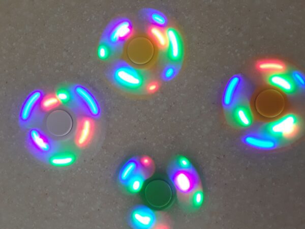 A group of four fidget spinners with lights on them.