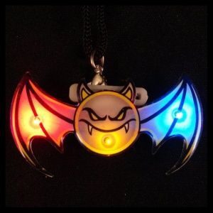 A bat shaped light up necklace with a smiling face.